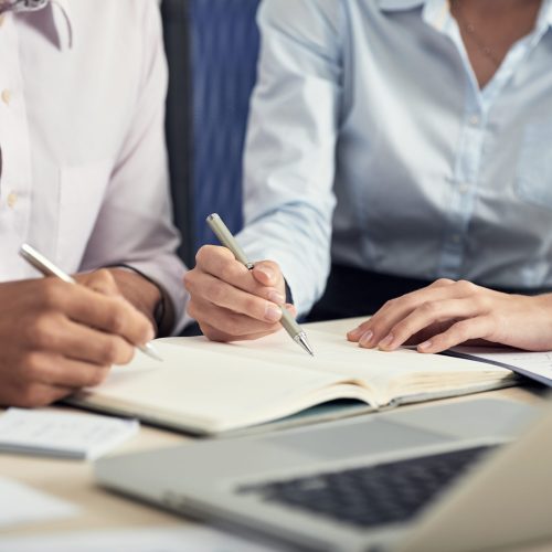 seccion-intermedia-de-dos-colegas-haciendo-una-lluvia-de-ideas-y-tomando-notas